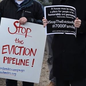 Two people holding signs that protest the eviction pipeline