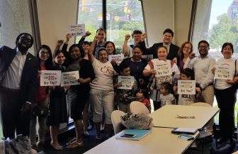 ff15-rice-meeting-07-16 a group of people pose with FF15 signs