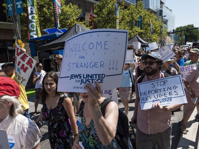 woman holding sign reading welcome the stranger